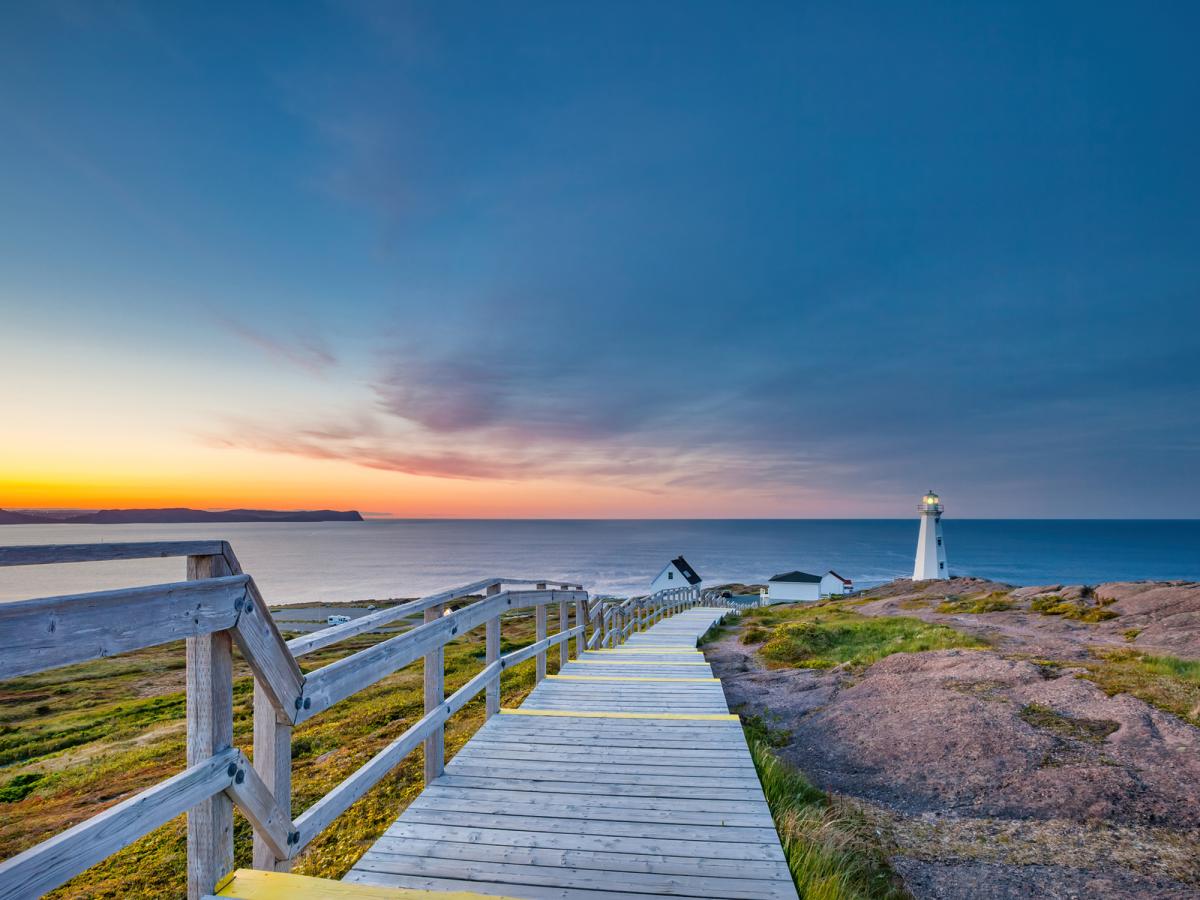 board walk along ocean with lighthouse in background